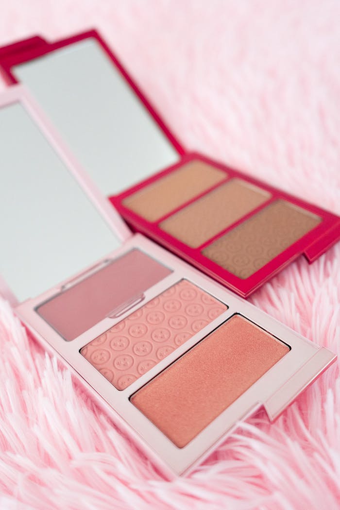 services-02 Flat lay of elegant makeup palettes on pink fluffy surface with mirrors.